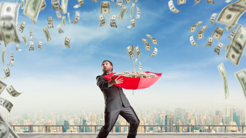 Businessman with umbrella full of money and money are falling