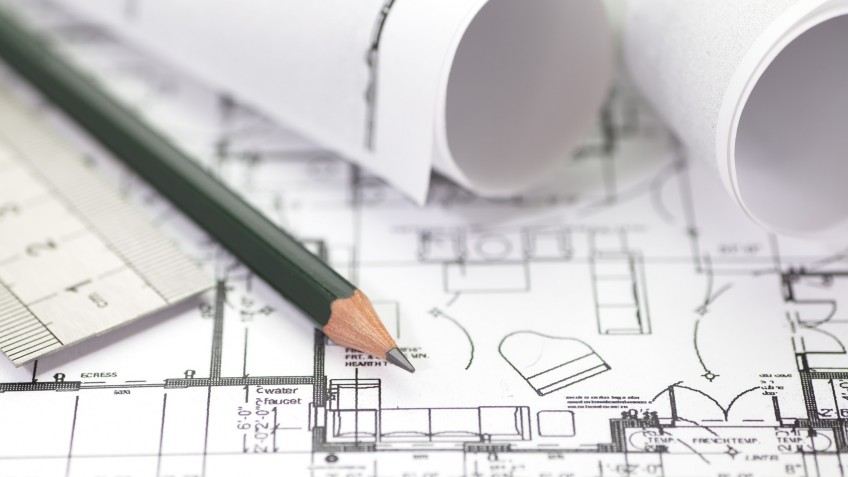 Architect rolls and plans construction project drawing