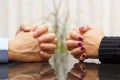 Man and woman sits at a desk with hands clasped. marital problem