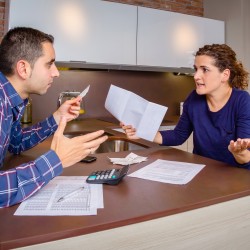 Angry young couple arguing by credit card debts