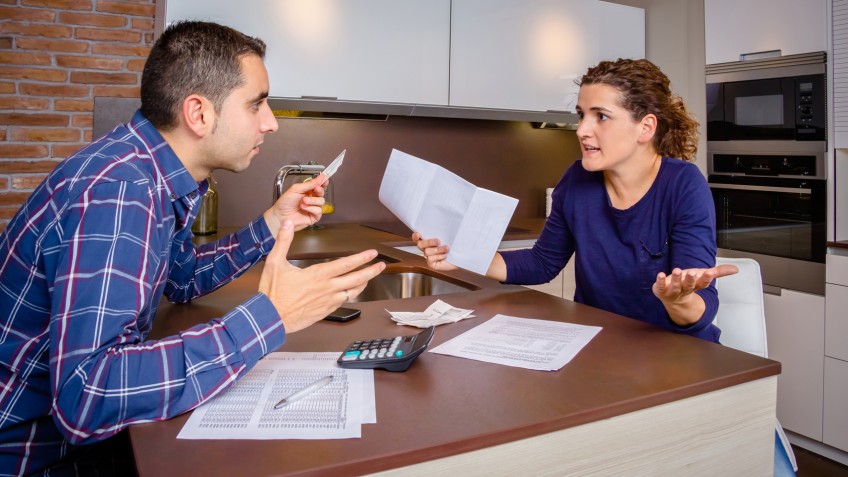 Angry young couple arguing by credit card debts