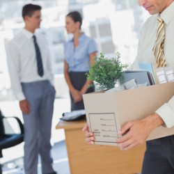 Businessman leaving office after being laid off carrying box of his things