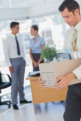 Businessman leaving office after being laid off carrying box of his things