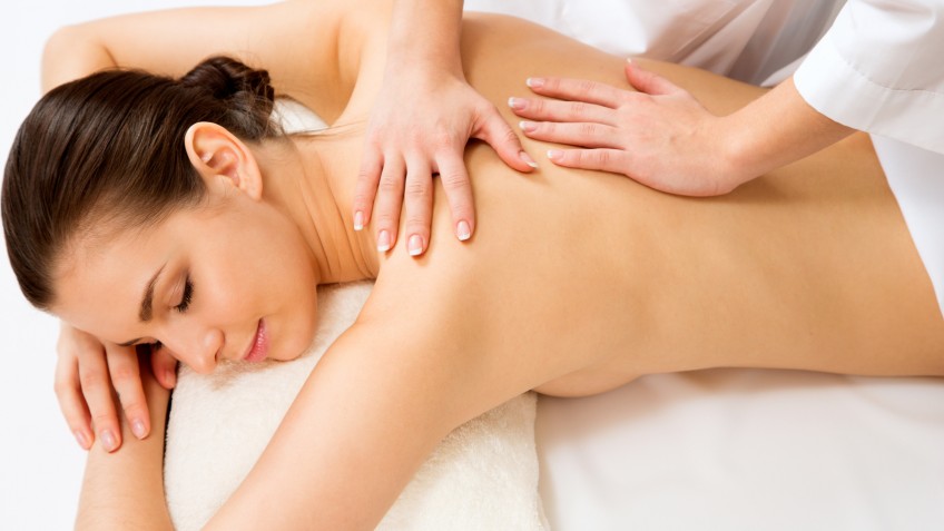 Masseur doing massage on the back of woman in the spa salon.