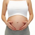 close up of pregnant woman touching her bare tummy