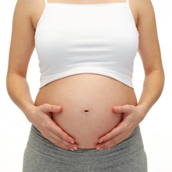 close up of pregnant woman touching her bare tummy