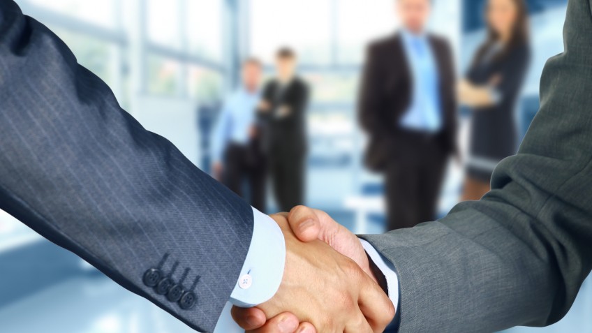 Business associates shaking hands in office