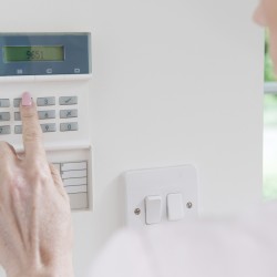 Woman Setting Control Panel On Home Security System