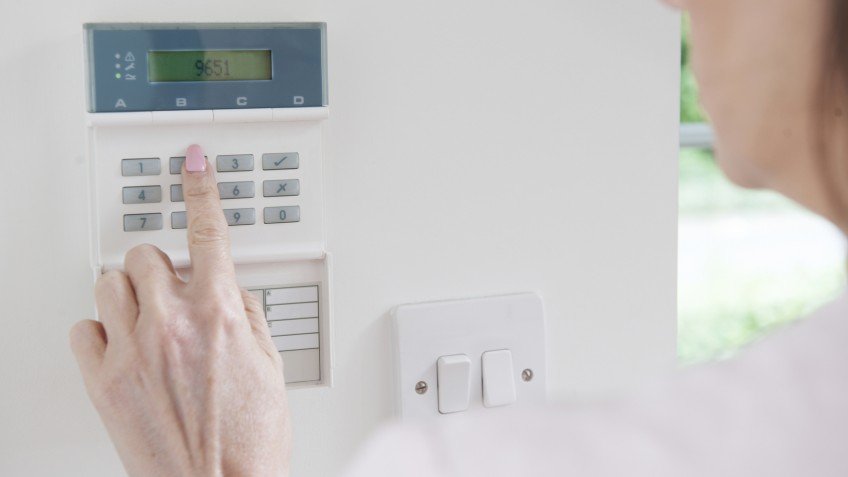 Woman Setting Control Panel On Home Security System