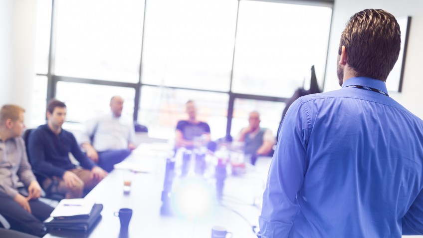 Business man making a presentation at office. Business executive delivering a presentation to his colleagues during meeting or in-house business training, explaining business plans to his employees.