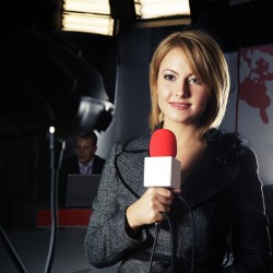 smiling television news reporter in live transmission with braking news in studio