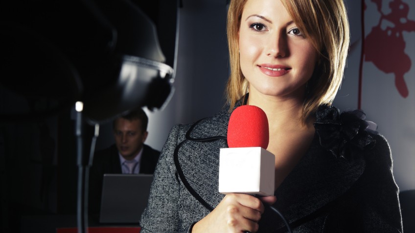 smiling television news reporter in live transmission with braking news in studio