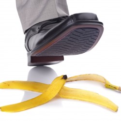 Businessman foot about to slip and fall on a banana skin