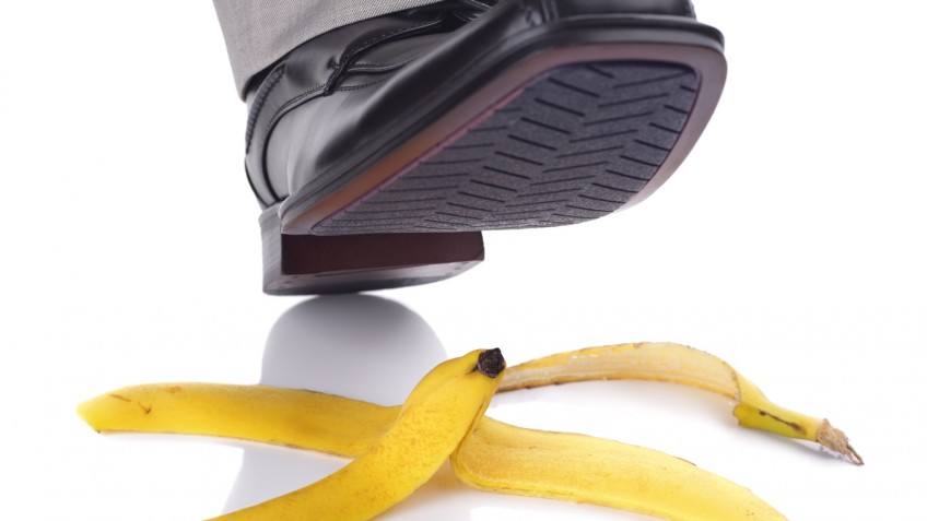 Businessman foot about to slip and fall on a banana skin