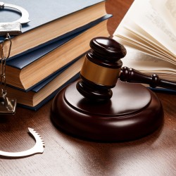 Gavel, books and handcuffs on wooden table