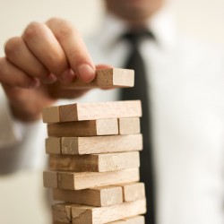 Businessman putting last block to the tower