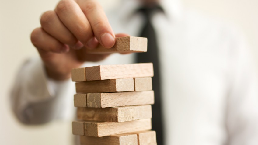 Businessman putting last block to the tower