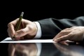 Businessman writing a letter, notes or correspondence or signing a document or agreement, close up view of his hand and the paper