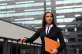 Beautiful business woman with catalog at modern building background