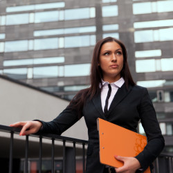 Beautiful business woman with catalog at modern building background