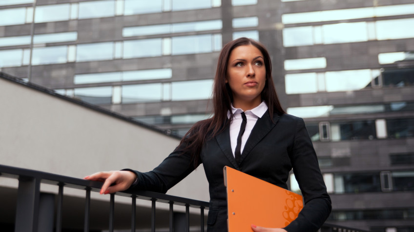 Beautiful business woman with catalog at modern building background