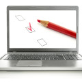 Laptop with red pencil and check boxes on screen. Online survey concept.