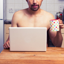 Naked man at home with laptop and coffee