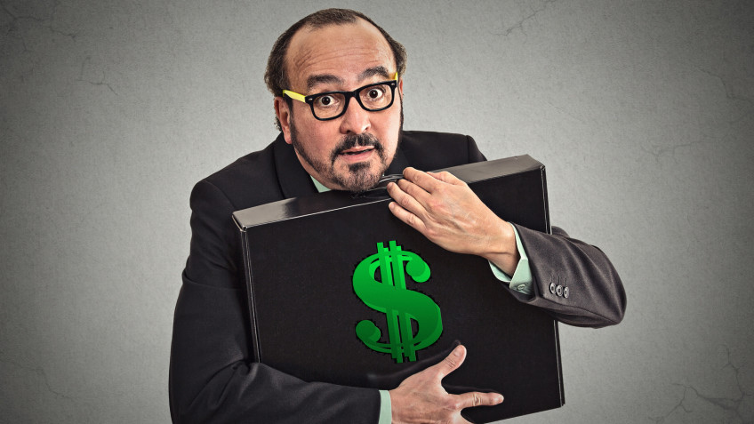 Money greed. Business man holding holding case with dollars tightly isolated on grey wall background. Worship, miser, excessive gain, finance concept