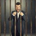 angry screaming businessman behind the prison cell over dark background