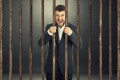 angry screaming businessman behind the prison cell over dark background