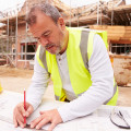 Construction Worker Looking At Plans On Building Site