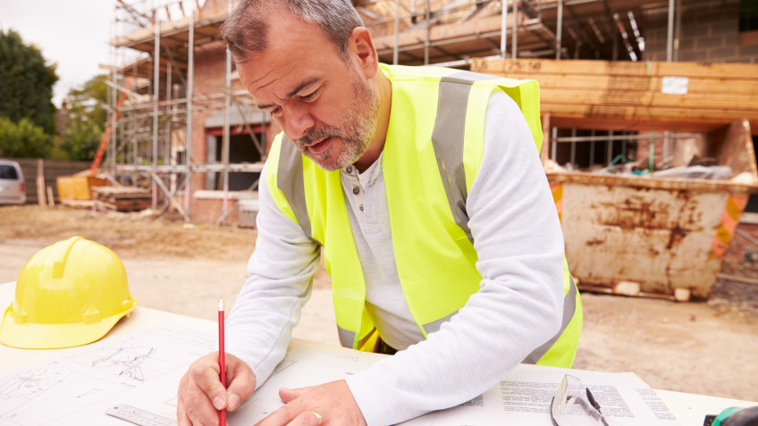 Construction Worker Looking At Plans On Building Site