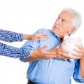 Senior man protecting piggy bank, savings from being stolen