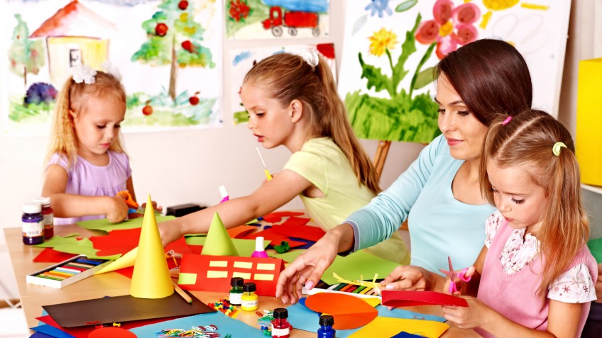 Children  cutting out scissors paper in preschool.