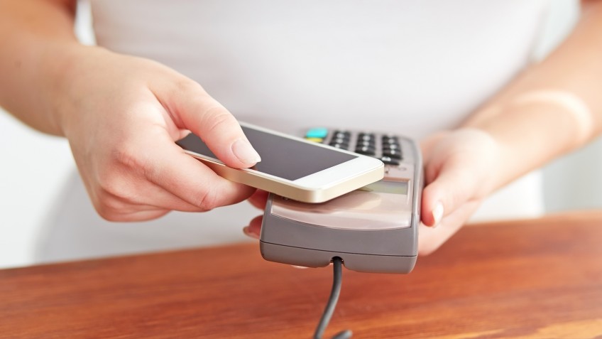 Woman paying with NFC technology on mobile phone