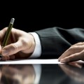 Businessman writing a letter, notes or correspondence or signing a document or agreement, close up view of his hand and the paper