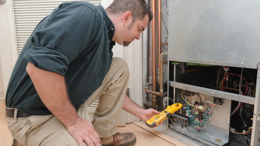 HVAC technician using a meter to check heat pump amperage