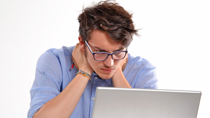 Hombre joven preocupado trabajando en un ordenador porttil.